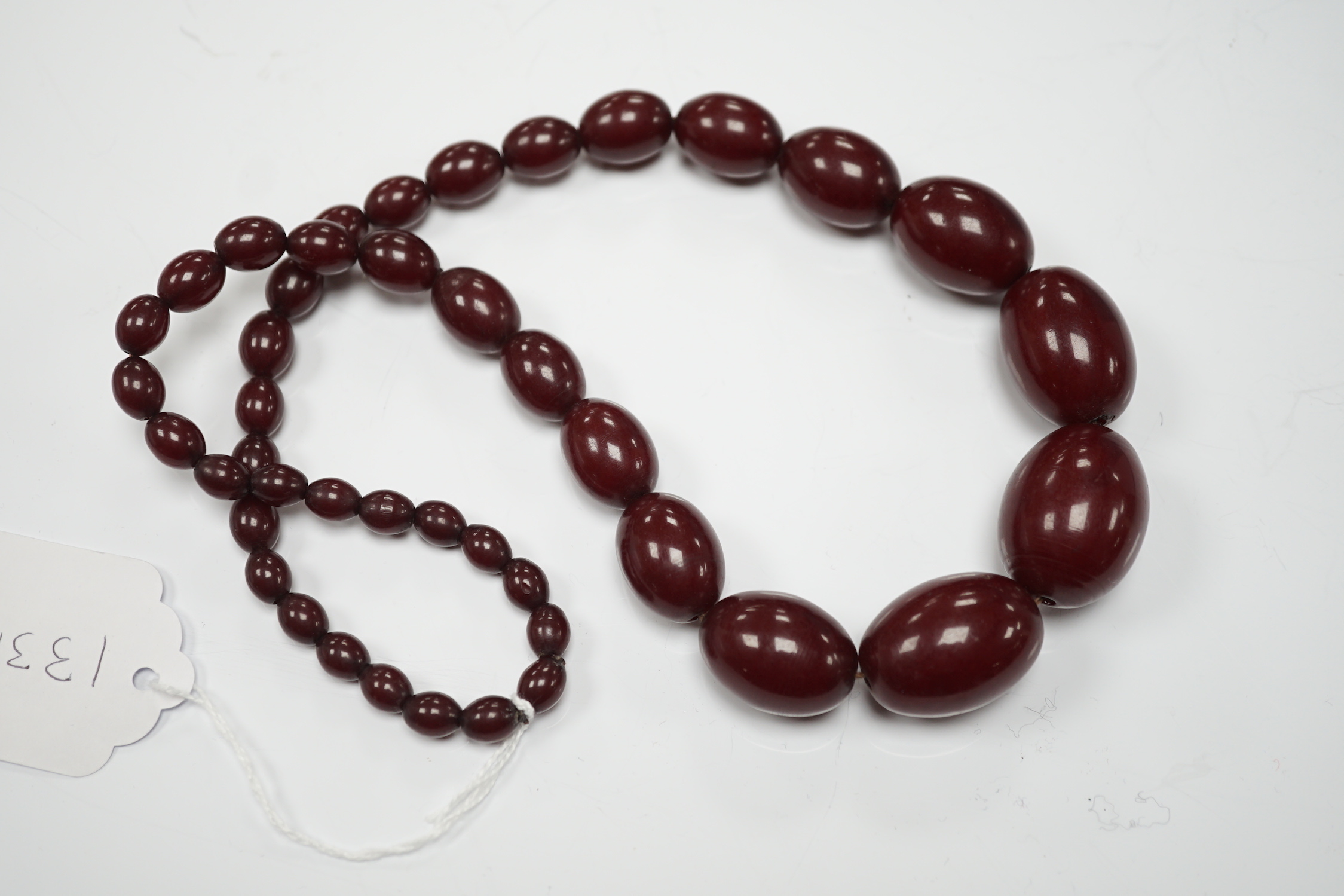 A single strand graduated simulated oval cherry amber bead necklace, 58cm, gross weight 80 grams.